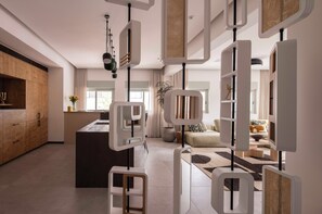 Uma cozinha moderna com uma ilha central, uma sala de jantar com sofá e mesa, e uma sala de estar com uma janela ampla.