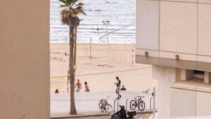A view of a beach with people, a palm tree, and bicycles. - Hayarkon 70 - Boutique Aparthotel (Tel Aviv)