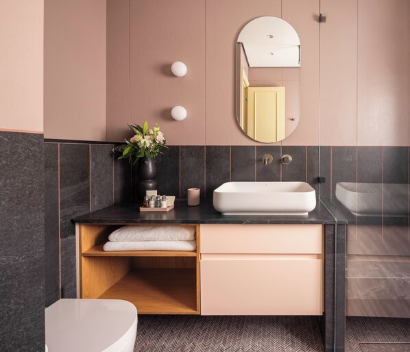 A modern bathroom with a white sink, dark tiles, a wooden shelf, and a mirror. - Hayarkon 70 - Boutique Aparthotel (Tel Aviv)