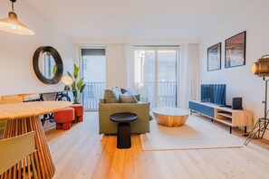 A modern living room with a sofa, coffee table, and a dining area with chairs and a table. - Bonjardim Suite | Central Accommodation Near Bolhão Market   (Porto)