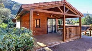 A wooden cabin with a porch, large windows, and a door. - L'Oasis provençale - Joli chalet avec terrasse (Solliès-Toucas)