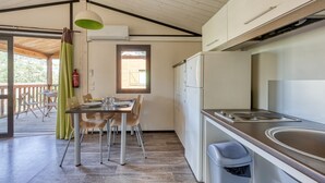 A compact kitchen with a built-in oven, a sink, and a dining area with a table and chairs. - L'Oasis provençale - Joli chalet avec terrasse (Solliès-Toucas)