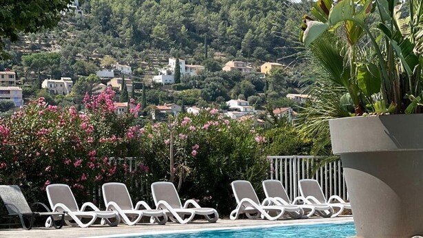 A swimming pool with lounge chairs, a view of houses on a hillside, and lush greenery. - L'Oasis provençale - Joli chalet avec terrasse (Solliès-Toucas)