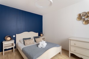 Une chambre à coucher comprenant un lit, des tables de chevet, une commode et un élément décoratif mural.