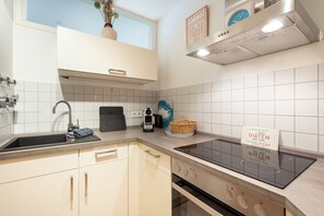 A modern kitchen with a built-in stove, a sink, and a window above the countertop. - Elbappartement Dresden – Modern Apartment Near the Elbe with Terrace and Garden Access (Dresden)