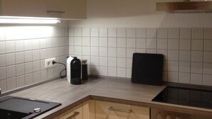 A kitchen with a stove, oven, and a clock on the wall. - Elbappartement Dresden – Modern Apartment Near the Elbe with Terrace and Garden Access (Dresden)