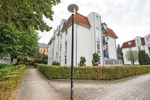 A residential building with a paved pathway, a hedge, and a street lamp. - Elbappartement Dresden – Modern Apartment Near the Elbe with Terrace and Garden Access (Dresden)