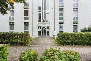 A modern building with a central entrance, multiple windows, and a paved pathway leading to the entrance. - Elbappartement Dresden – Modern Apartment Near the Elbe with Terrace and Garden Access (Dresden)