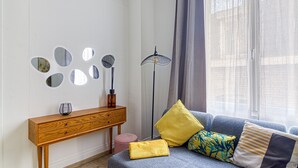 A modern living room with a sofa, cushions, a wooden console table, and wall-mounted mirrors. - L  ’Attitude Mer - À 20 m de la plage (Bray-Dunes)
