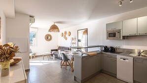 Ett modernt kök med inbyggd mikrovågsugn, diskmaskin och en matplats med bord och stolar.