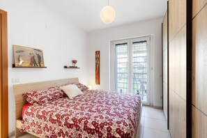 Un dormitorio con cama, un cuadro, una ventana y una puerta.