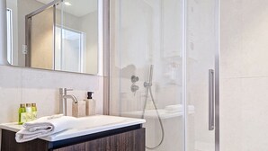 A modern bathroom with a glass shower enclosure, a white sink with a dark wood vanity, and a large mirror above the sink. - N&J - STUDIO ANNA - Central Nice • AC • Walk to beach (Nice)