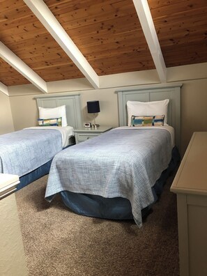 Een slaapkamer met twee bedden, een nachtkastje met een lamp en een kledingkast.