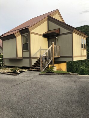 Ein zweistöckiges Haus mit einer Holztreppe und einer kleinen Veranda.