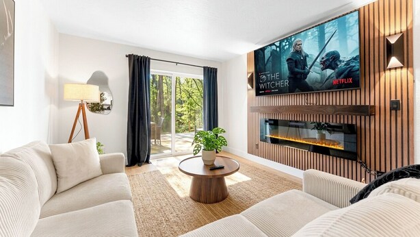 A modern living room with a flat-screen TV, a fireplace, a sofa, and a dining table.