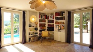 Una habitació amb una biblioteca, una cadira i una finestra gran.