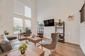 Ein Wohnzimmer mit Sofa, Couchtisch, Sessel, Fernseher und Regalelement.