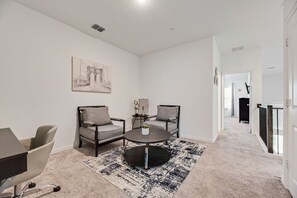 A modern living room with a round coffee table, two armchairs, a sofa, and a painting on the wall. - FS832 | Frisco Retreat | 2BD | Universal Kids Resort (Frisco)