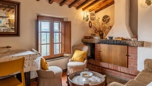 Un ambiente acogedor con chimenea, vigas de madera, una mesa de comedor y un rincón de estar confortable.