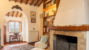 Una sala de estar acogedora con chimenea, estanterías de madera, un tapete estampado y un comedor con ventanal.