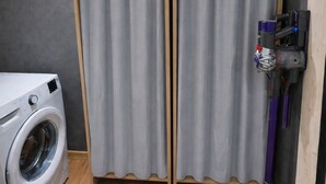 A laundry area with a washing machine, two grey curtains, and a vacuum cleaner. - Comfortable 15-person apartment near the ski slopes. Parking lots (Saint-Sorlin-d'Arves)
