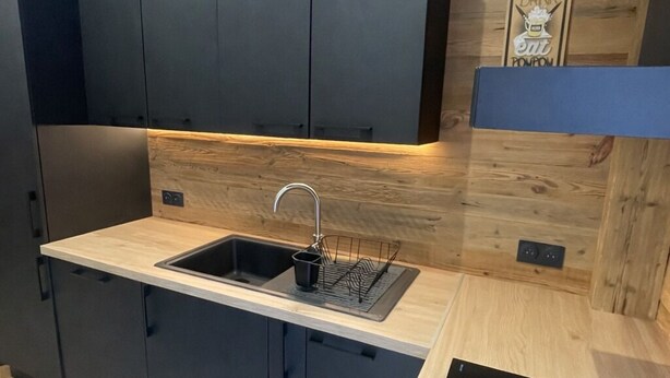 A modern kitchen with a black countertop, a sink, and a black stove. - Comfortable 15-person apartment near the ski slopes. Parking lots (Saint-Sorlin-d'Arves)