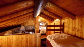 Un interno in legno con tetto a falde, un letto, una scala e una finestra.