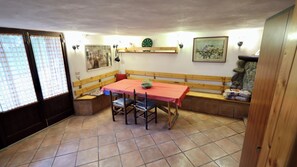 Zona pranzo con tavolo, panche e pavimento piastrellato.