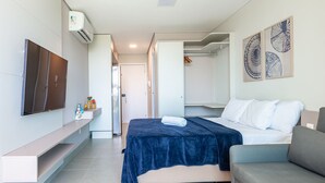 A modern hotel room with a bed, a sofa, a TV, and a wardrobe. - Beachclasssummer #c215 - Studio by Carpediem (Ipojuca)