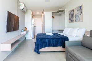 A modern hotel room with a bed, a sofa, a TV, and a wardrobe. - Beachclasssummer #c215 - Studio by Carpediem (Ipojuca)