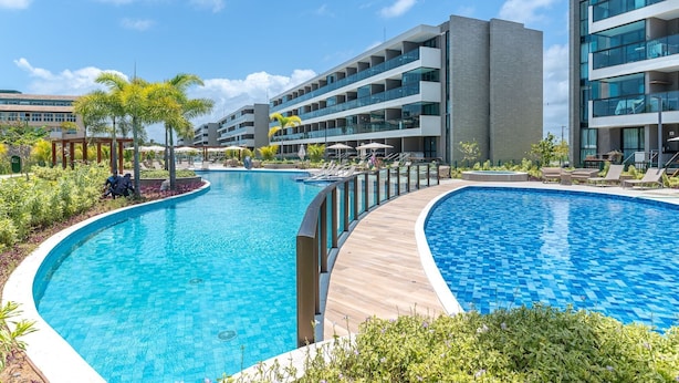 Un hôtel moderne doté d’une grande piscine, de nombreux balcons et d’un jardin bien entretenu.