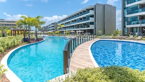 A modern hotel with a large swimming pool, multiple balconies, and a well-maintained garden area. - Beachclasssummer #c215 - Studio by Carpediem (Ipojuca)