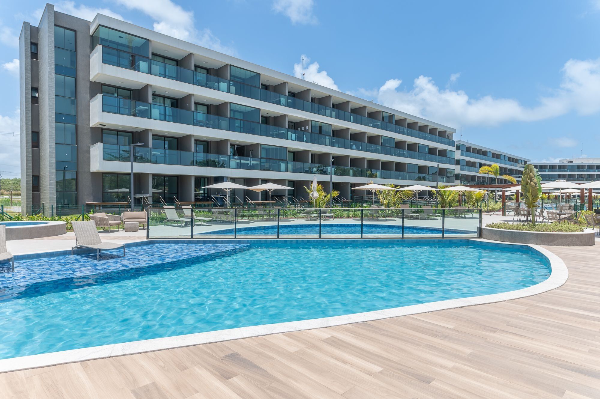 Un hotel moderno con piscina, varios balcones y zonas de estar al aire libre.