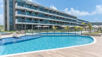 Un hotel moderno con piscina, varios balcones y zonas de estar al aire libre.