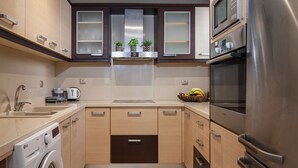 Eine moderne Küche mit Waschmaschine, Mikrowelle, Backofen und einer Obstschale auf der Arbeitsfläche.