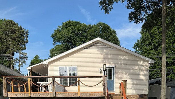 A wooden deck leading to a house with a porch and a covered entryway. - Spend time with family & friends. Fish, swim, kayak, or relax on private dock! (Lexington)