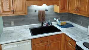 A kitchen with wooden cabinets, a black sink, and a marble countertop. - Spend time with family & friends. Fish, swim, kayak, or relax on private dock! (Lexington)