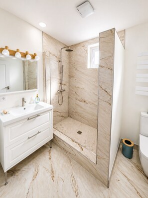 A modern bathroom with a glass-enclosed shower, a white vanity with a mirror, and a toilet. - Coastal Retreat Steps from the Sea 2BR • 2BA (Almuñécar)