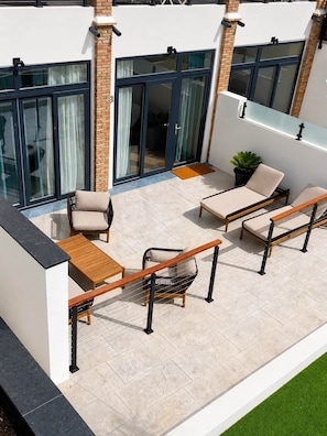 Une terrasse sur le toit, avec un espace salon, une petite table et un pot de fleurs.