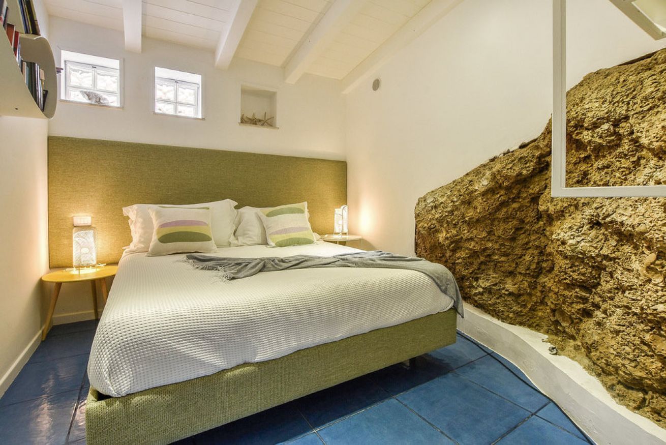 Ein Schlafzimmer mit einem Bett, Nachttischlampen, einer Wand mit Struktur und einem Fenster.