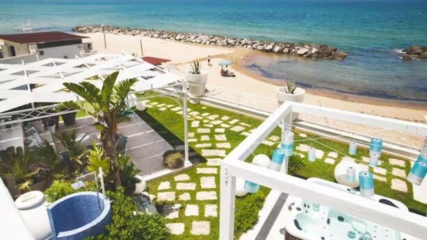 A hotel with a pool, a beach view, and a garden area with potted plants. - Riva Estate Villa by LeDhome (Trappeto)