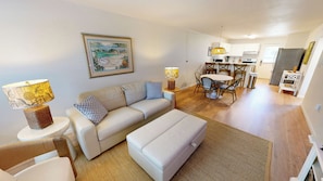 A modern living room with a sofa, ottoman, and a dining area with chairs and a table. - Beautiful Ground Floor Venus 119 (Fort Walton Beach)