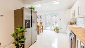 Una cocina moderna con un refrigerador integrado, una mesa de comedor de madera y un piso de vidrio corredizo que da a un jardín.