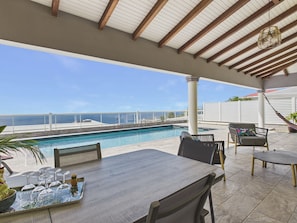A covered outdoor area with a pool, seating, and a view of the ocean. - Single-storey house with pool & sea view, sleeps 6 (Sainte-Luce)