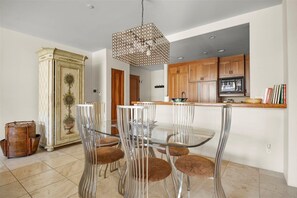 A modern kitchen with wooden cabinets, a glass dining table, and a unique pendant light. - Mountain Village Gem | Ski-In/Out + Steam Shower (Mountain Village)