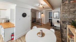 Una cocina moderna con encimeras de madera, una zona de comedor con una mesa redonda y una pared de piedra.
