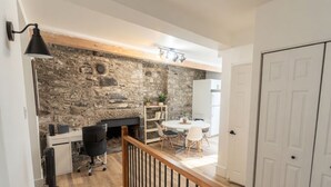 Un interior moderno con una pared de piedra, una zona de comedor y una puerta blanca.
