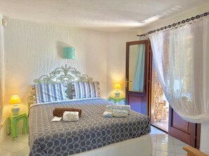 Ein Schlafzimmer mit einem Bett, zwei Nachttischen, einer Tür und einem Vorhang.