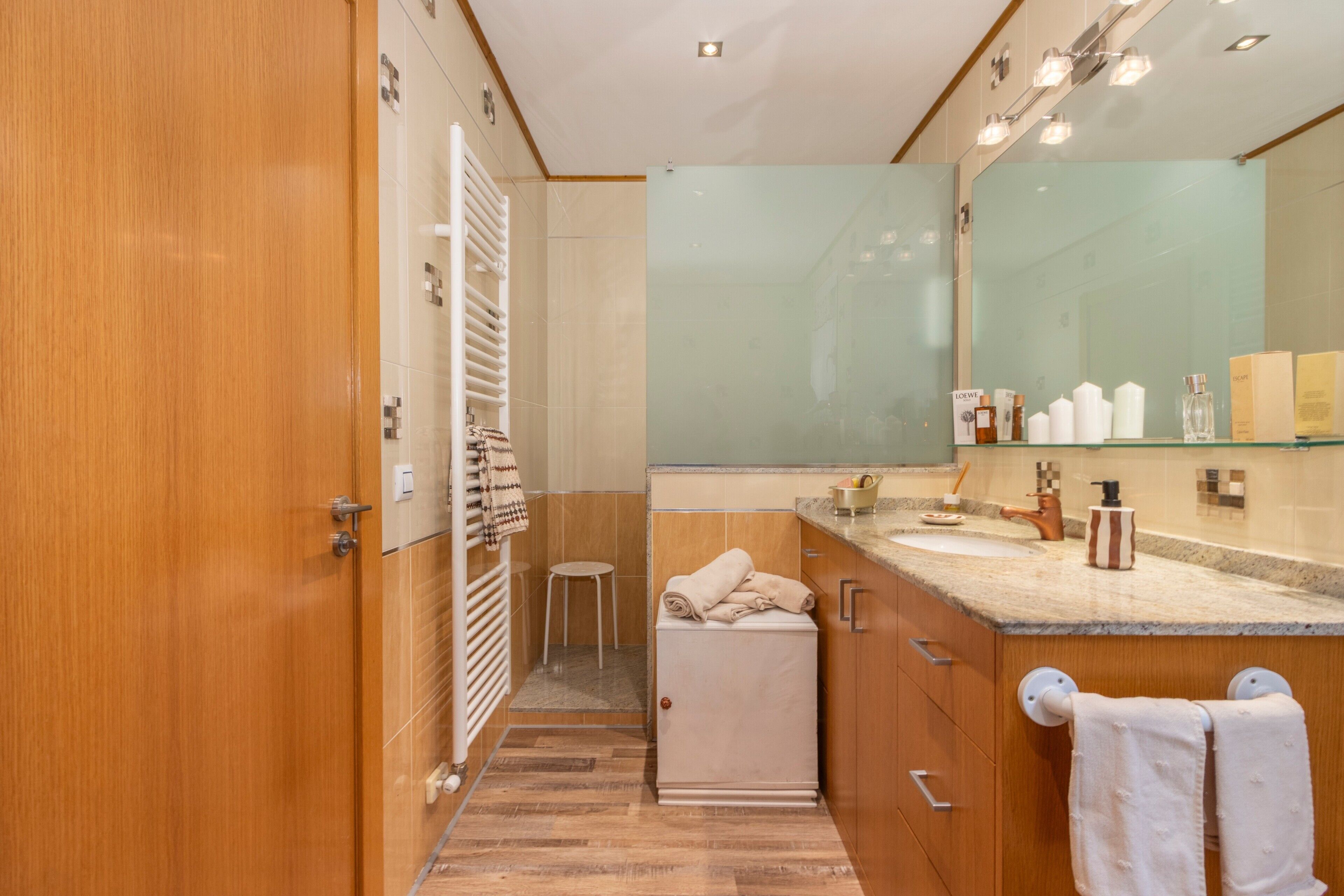 Ein modernes Badezimmer mit einem Holz-Waschtisch, einem großen Spiegel und einem Handtuchhalter.