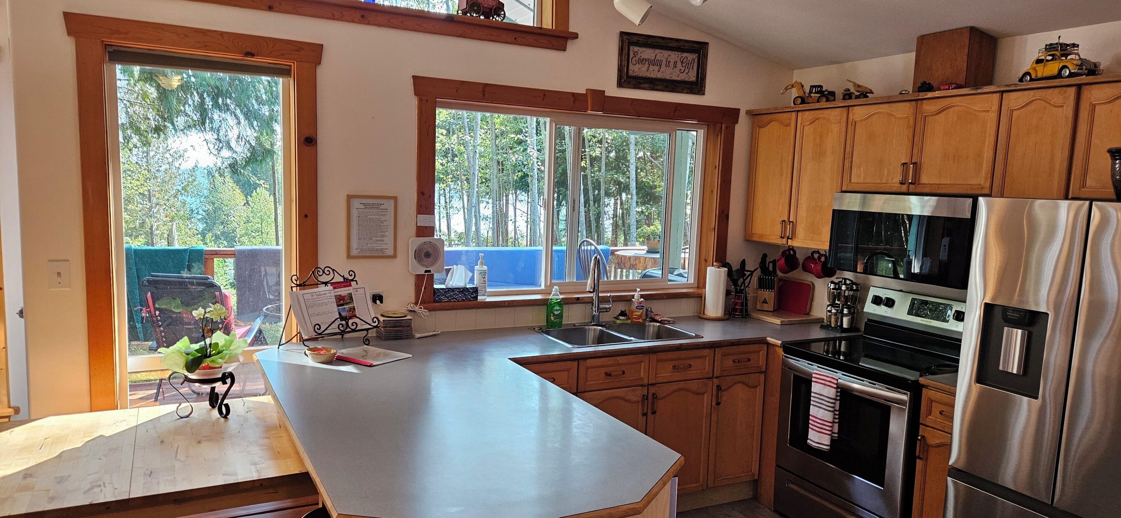 A kitchen with wooden cabinets, a stainless steel refrigerator, and a large window.